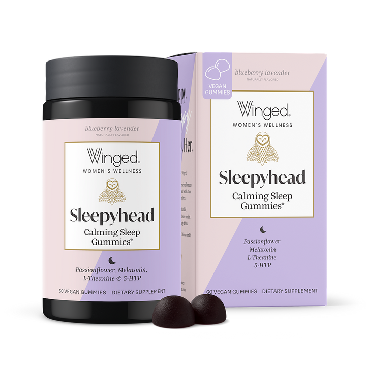 A package of Sleepyhead Calming Sleep Gummies by Winged Wellness, with two gummies in front of the box and an unboxed package of Sleepyhead. The box is purple and pink with product information and branding.