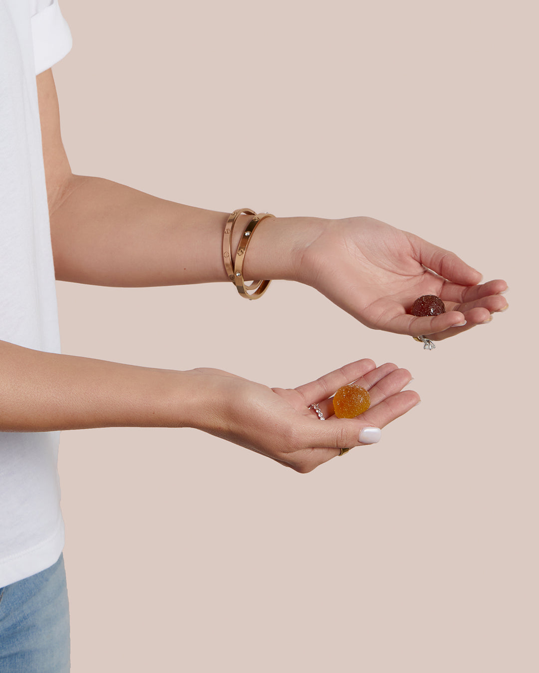 A woman holding a Winged Relaxation gummy and a Winged Sleep gummy in the palm of each hand